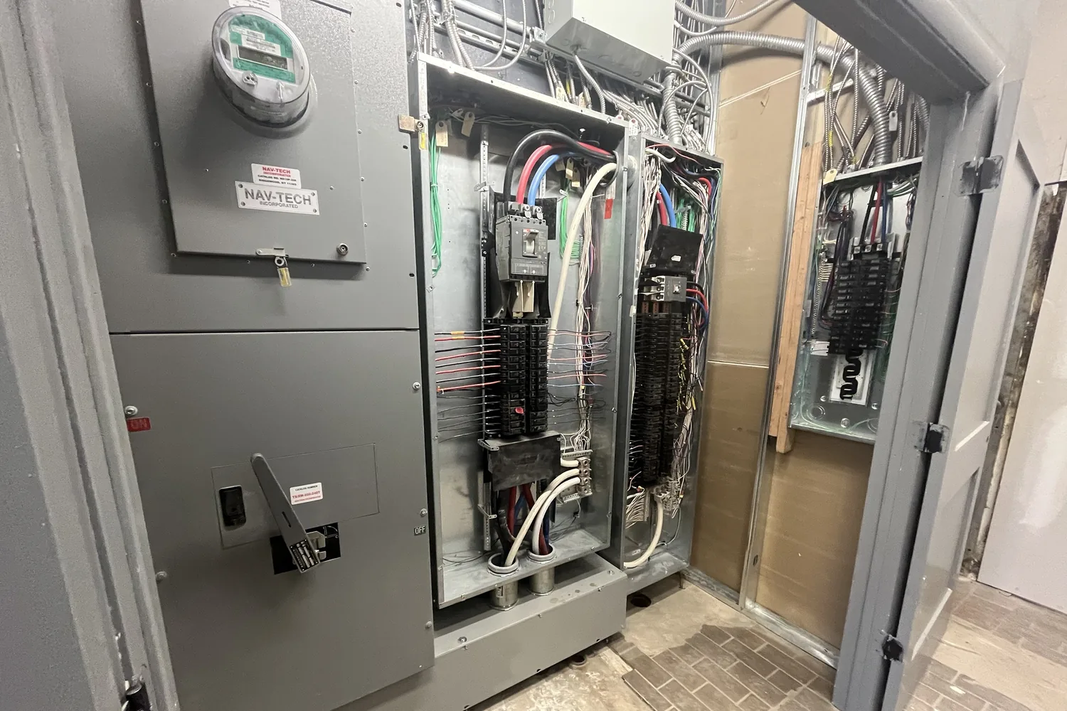 A service switch, meter and new distribution panels in an electrical room, covers off during installation